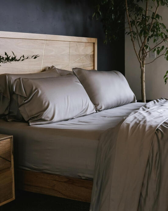 Luxury viscose-from-bamboo sheet set in soft dove grey on neutral bedding, styled in a cozy modern farmhouse bedroom.