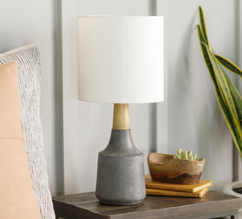 Textured ceramic base with a neutral linen shade — understated elegance for any nightstand or console. Petite ceramic table lamp with linen shade on wood dresser styled with books and greenery.