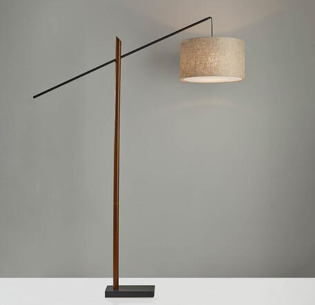 Walnut arm, woven rattan shade, and adjustable height bring warmth and calm to any reading space. Mid-century rattan shade floor lamp with walnut arm and black base beside reading chair in neutral room.