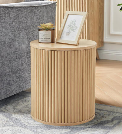 Compact, beautifully carved, and practical — this boho-inspired table doubles as hidden storage for books or cozy essentials. Round fluted nightstand or accent table in light oak with hidden storage, styled beside a cozy chair.