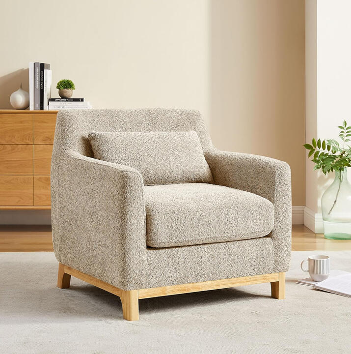 Warm camel bouclé reading chair with deep seat, matching lumbar pillow, and solid wood legs — cozy accent chair for bedroom or reading nook.
